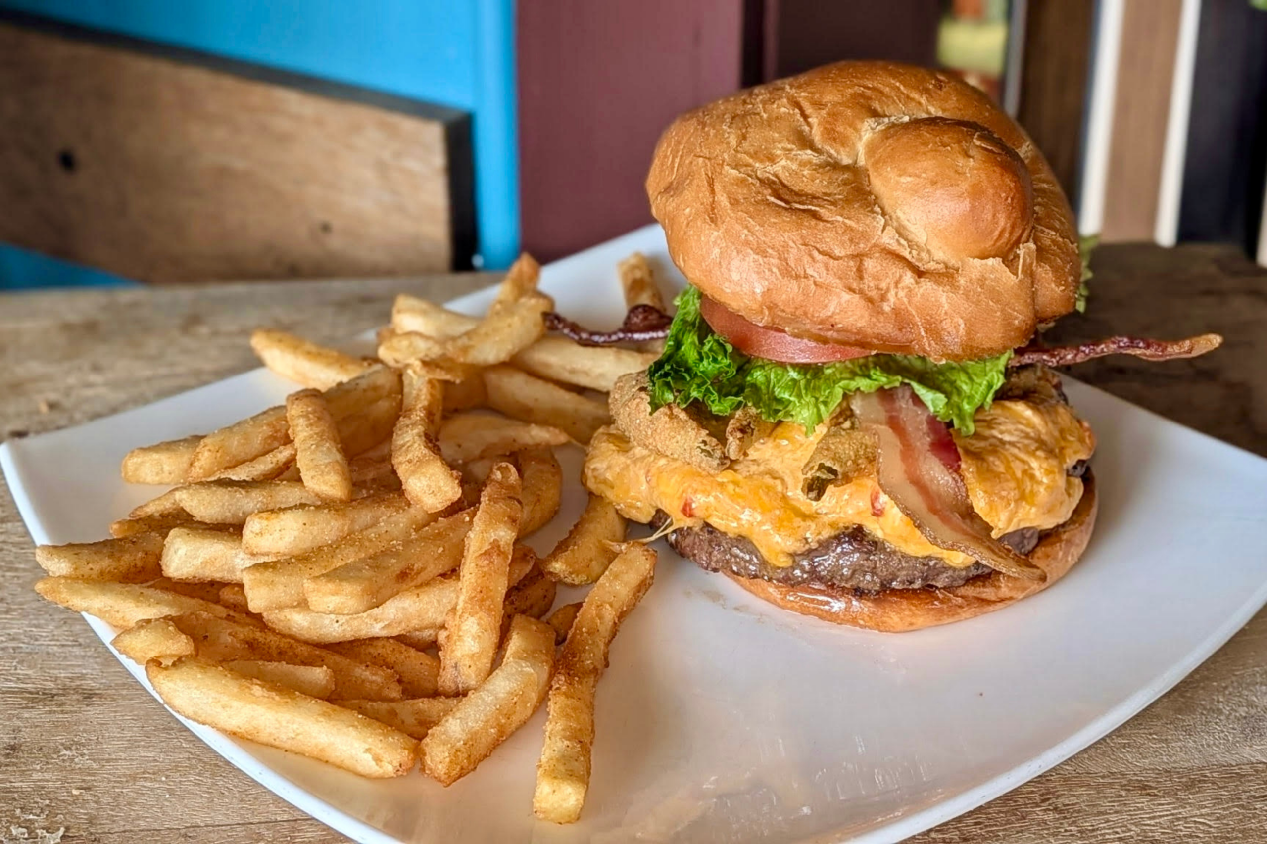 The Carolina Crunch Burger sits on a plate next to golden, crispy French fries.